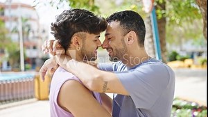 Two men couple smiling confident hugging each other at park
