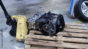 Automatic transmission stands on wooden pallet in service center. Hydraulic trolley moves equipment around hall to speed up repair process