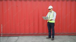 Foreman using laptop computer checklist inventory and control loading Containers box at warehouse logistic in Cargo freight ship for import export. shipping loading in docks.