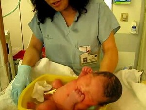 Newborn baby falls asleep during his first bath
