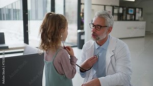 Doctor examining little girl's ear using otoscope, looking for infection. Friendly relationship between the doctor and the child patient.