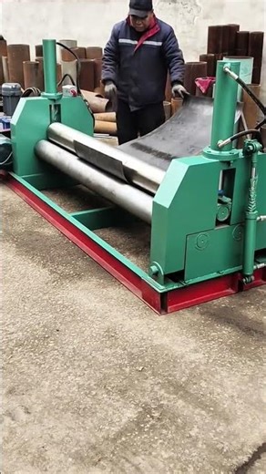 operating a plate rolling machine to bend a large metal sheet into a curved shape for fabrication