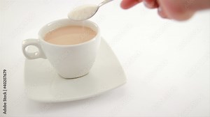 adding sugar to a cup of coffee and milk