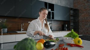 Young woman cooking, dancing at kitchen. Female cook food listen to music with headphones and dancing in the kitchen. Girl with vegetables play radio and dance, while cooking salad have fun at home.