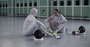 Sportswomen talking during break in fencing workout