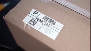 Applying a Shipping Label on a Mail Shipping Box Closeup