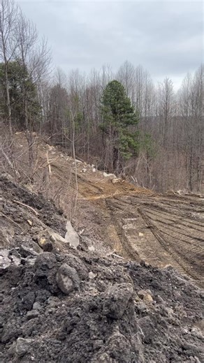 Excavator Struggles on Rocky Slope in Forest