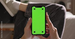 Woman enjoys freedom smartphone provides, with green screen mock-up various applications, vertical mode. Advertising app. Tap in center to start watching video content. Entertainment and social media