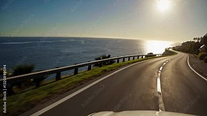 The camera captures a first-person POV from the driver’s seat as the car cruises along a scenic coastal highway.