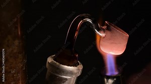 Marijuana concentrate usage up close macro. Dab rig demonstration shows heating of glass bowl, then glass rod with small amount of thc concentrate is dropped in and vaporized in paraphernalia.