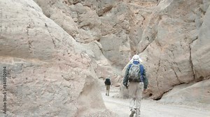 Two male hikers walk through the Titus Canyon Narrows in Death Valley National Park in California.
