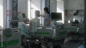 Emergency room with modern equipment in clinic. Elderly man in oxygen mask sleeps in bed after surgery. Nurse uses and adjusts life support machine for patient. Intensive care department in hospital.