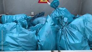 Clinical waste in hazard bags are squeezed together in a press. Concept: Health and hospital waste