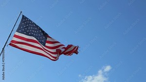 American Flag blowing in the wind with a blue sky background. USA American Flag. Waving United states of America famous flag in front of blue sky. Memorial Day - American concept.