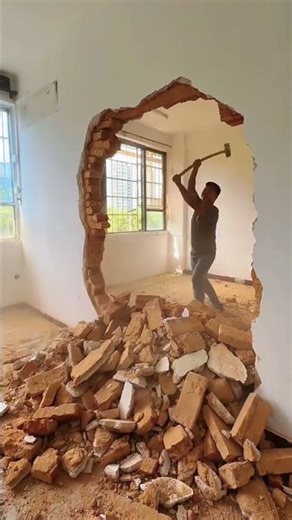 Demolition Worker Breaking Down Interior Wall Bricks With Hammer