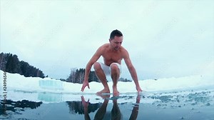 Young man swims in the ice hole. Slow motion version of the clip.