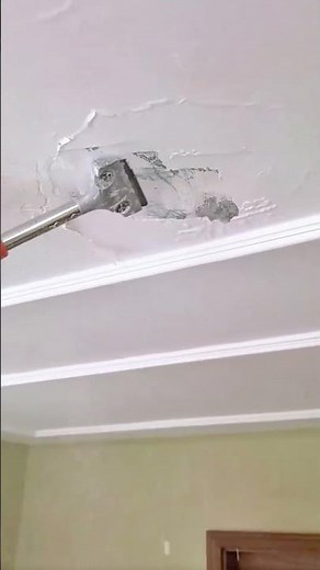 Removing damaged ceiling plaster using scraper for smooth repair