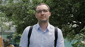 Handsome college student walking by at college park with backpack.