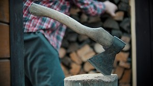 Ax stuck in a log while a lumberjack works - Free Stock Video