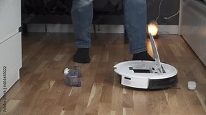 Housework and technology concept. Maintenance and service of robot vacuum cleaner. Cleaning, repair, replacement of parts. Man repairing robot cleaner at home. Smart home functions, fully automated