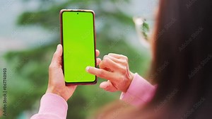 4K shot of Young woman using smart phone with green screen. using phone outdoors. Green screen mockup template of Mobile phone, Chroma key.