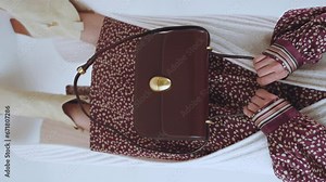 Elegant handbag in a woman's hand, a girl with a beautiful handbag, a girl model posing with a handbag, a woman's bag, shooting in slow motion, vertical shooting