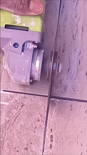Repairing ceramic tile joints with an electric grinder using professional precision.