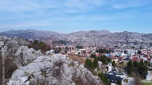 Cetinje, the old capital of Montenegro. Town in the mountains. Monastery, old church and red tiled roofs of houses. Aerial footage. Eagle cliff