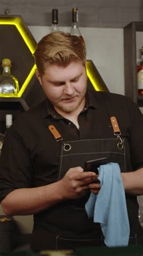 clip-4000020123-young-bartender-using-smartphone-while-leaning-on