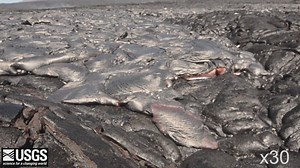 This video shows timelapse images of active pāhoehoe toes as the episode 61g lava flow from Puʻu ʻŌʻō advances across the coastal plain. The pāhoehoe flow front is very fluid and active. As the flow spreads across the ground, its surface cools and develops a hardened crust. Continued addition of new lava into the interior of the flow eventually raises and breaks through the rigid crust, allowing molten lava from the interior to escape through the new openings and spread forward. Note the rigid c
