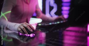 Close Up of a Female Gamer Girl Playing on a Computer. Focus on Hands Using Keyboard and Mouse. Streamer Sitting Behind a Futuristic Interactive Desk in a Colorful Neon Studio Room