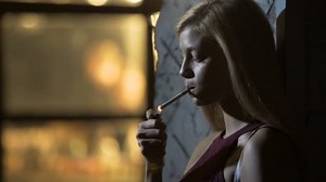 Beautiful sexy female lighting a cigarette and inhaling smoke, night life