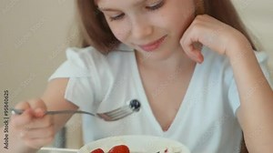 Girl eating blueberries from a plate and smiling at the camera