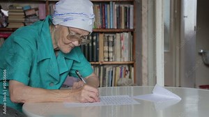 old woman writing letter then take off glasses Stock Video