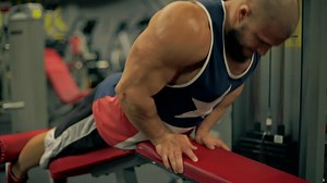 Bald athletic man beard engages in leg exercises using gym equipment. He focuses intently on his workout in modern fitness center during evening hours, does leg curls