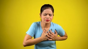 Young woman having heart attack, isolated on yellow background, heart pain, cardiac arrest concept