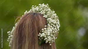 Flower crown made from the bride's flower (Gypsophila elegans) and worn by a women photographed in a beautiful green landscape during an outdoor wedding ceremony. 4k video natural wedding accessories.