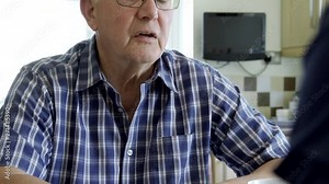 Woman Comforting Depressed Senior Man Sitting In Kitchen At Home