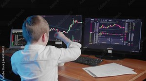 A rear view of a body sitting at a computer and looking at an online stock market chart showing bitcoin currencies. The boy rubs his eyes. In real time. Cryptocurrency. Investors