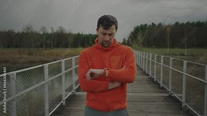 Runner using fitness smart watch to check time and heart rate on jogging to monitor health in outdoors. Athlete practices workout to keep wellness. Trail runner looking at heart rate monitor watch.