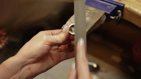 clip-3994695317-professional-jeweler-filing-silver-ring-on-workbench
