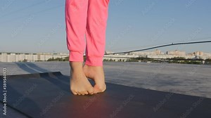gymnast's feet barefoot on the exercise mat. Girl athlete doing warm-up toes. She does gymnastics on the roof in the summer after sunrise. She is alone and free. 4k