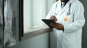 clip-12724901-doctor-standing-using-ipadtablet