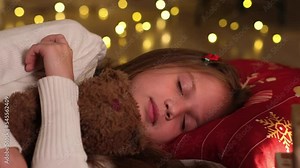 Waiting for Santa Claus. Adorable little girl sleeping on floor on Christmas night in cuddle with toy bear. Traditional family celebration, childhood and children dreams. Close up Stock Video