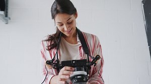 Female Crew Member On Video Film Set Operating Wireless Follow Focus Module In White Studio