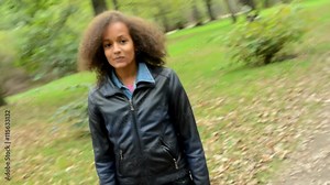 young charming african girl stand in the forest and camera rotate around her - she is smiling in to camera - eye contact