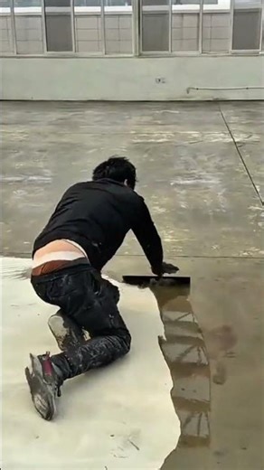 applying self leveling epoxy to a concrete floor using a squeegee for a building renovation project