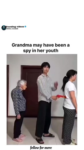 TRENDING VIDEOS on Instagram: "@follow_trends05 The video takes place in a simple indoor room with white walls, a brown door, and tiled floors, featuring an elderly woman with short gray hair wearing a floral-patterned top and black pants, standing alongside a young man in a striped shirt and black pants, and a young woman in a white t-shirt and checkered pants observing. It begins with the young man playfully holding a red toy gun to the back of the young woman's head, demonstrating a mock thre
