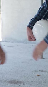 Male builder hands over a white hard hat to a fellow builder