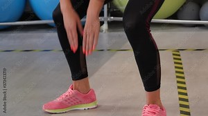 Close up female legs while squatting in fitness club. Fitness woman training squat exercise in gym class low view